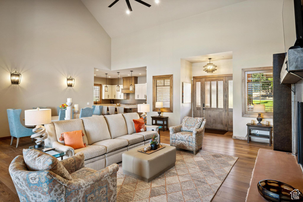 Living room with ceiling fan, high vaulted ceiling, and light hardwood / wood-style floors