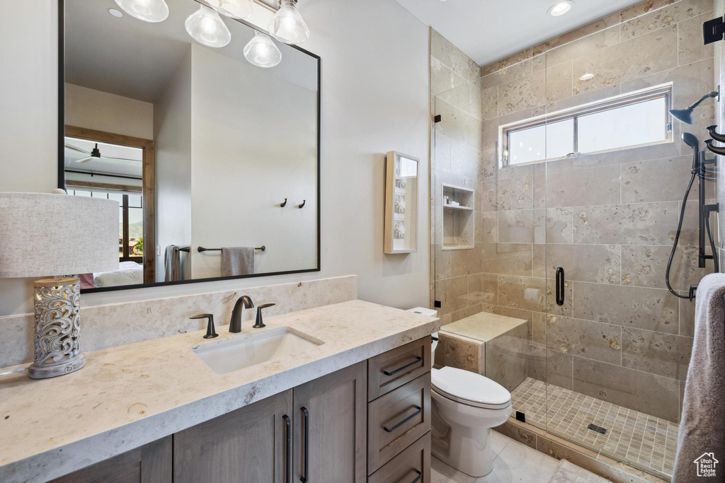 Bathroom with vanity, toilet, walk in shower, and tile patterned flooring