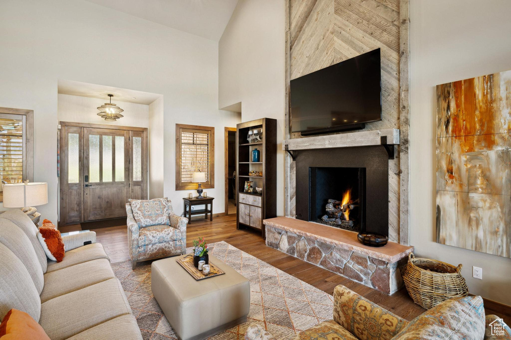 Living room with wood-type flooring, a fireplace, and high vaulted ceiling