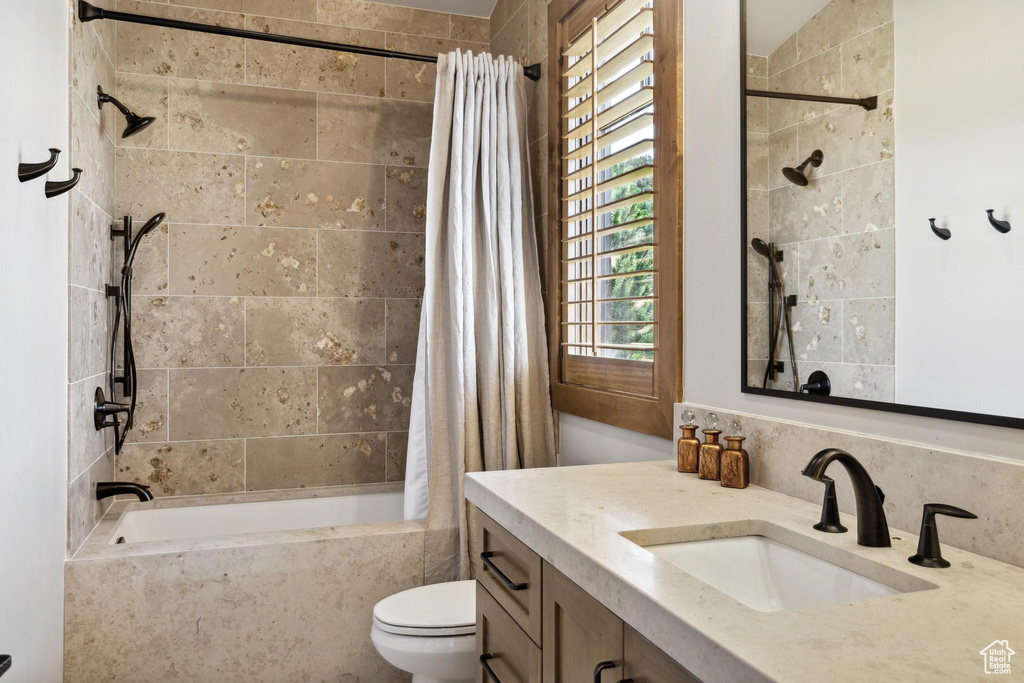 Full bathroom with toilet, shower / tub combo with curtain, and vanity