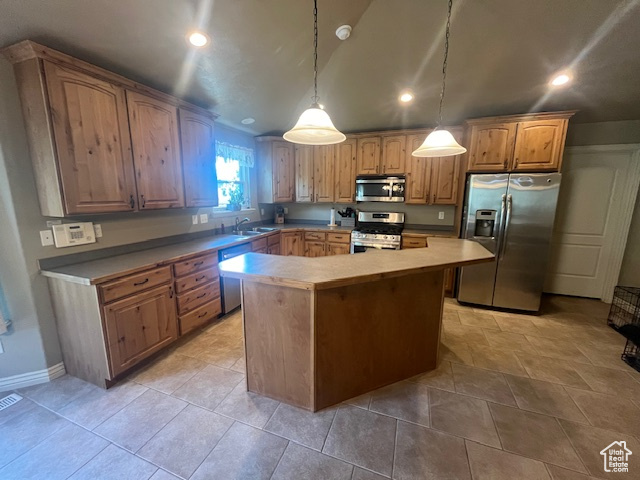 Kitchen featuring a kitchen island, sink, decorative light fixtures, and appliances with stainless steel finishes