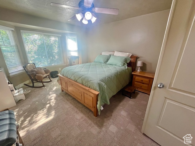 Bedroom with ceiling fan, carpet, and a textured ceiling