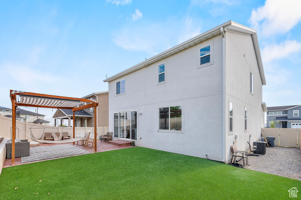 Rear view of house with central AC, a lawn, a patio, and a pergola