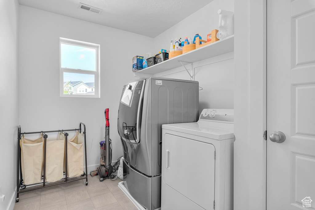 Washroom featuring light tile patterned flooring and washer and dryer