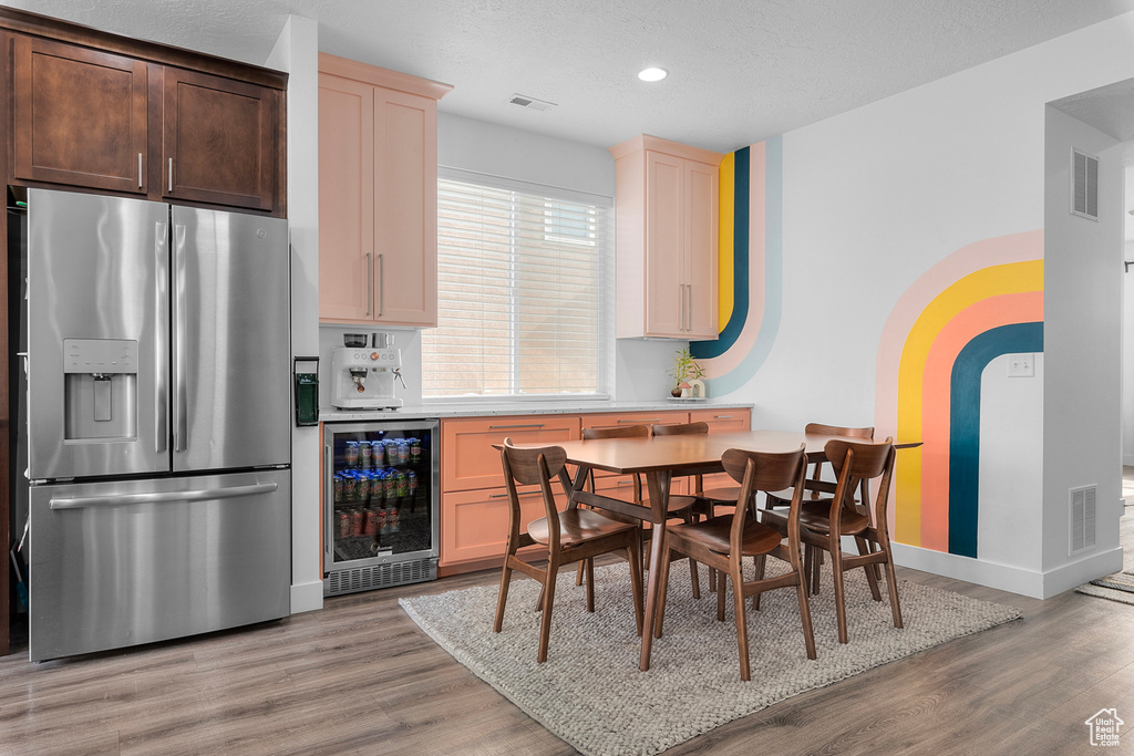 Dining space featuring wine cooler and light hardwood / wood-style floors