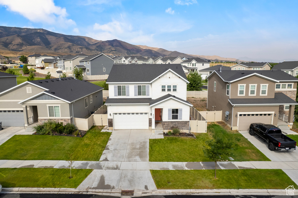 View of front of house featuring a garage, a front yard, and a mountain view