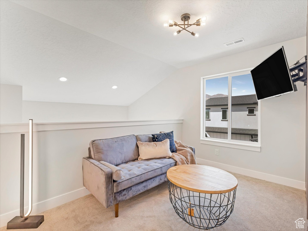 Living area featuring lofted ceiling, a notable chandelier, and light carpet