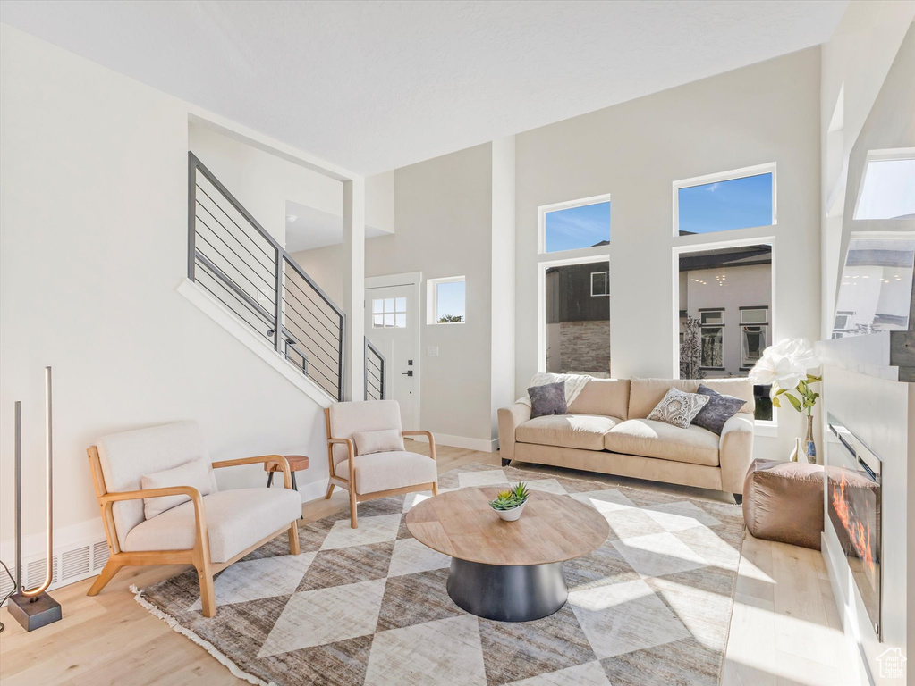 Living room with a wealth of natural light, a towering ceiling, and light hardwood / wood-style flooring