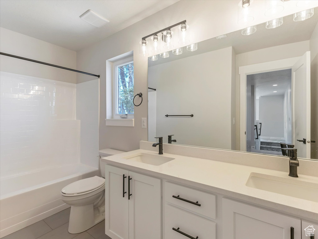 Full bathroom featuring dual vanity, shower / bath combination, toilet, and tile patterned flooring