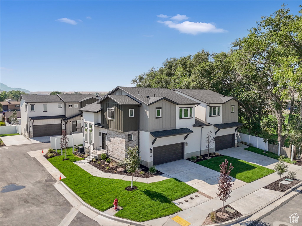 View of property featuring a front lawn, central AC unit, and a garage