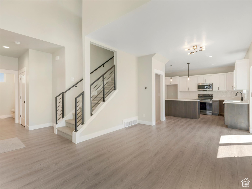 Unfurnished living room featuring sink and light hardwood / wood-style flooring