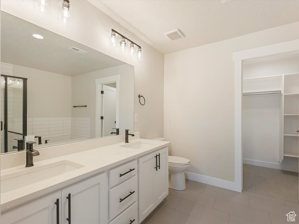 Bathroom with toilet, tile patterned floors, a bathing tub, and dual bowl vanity