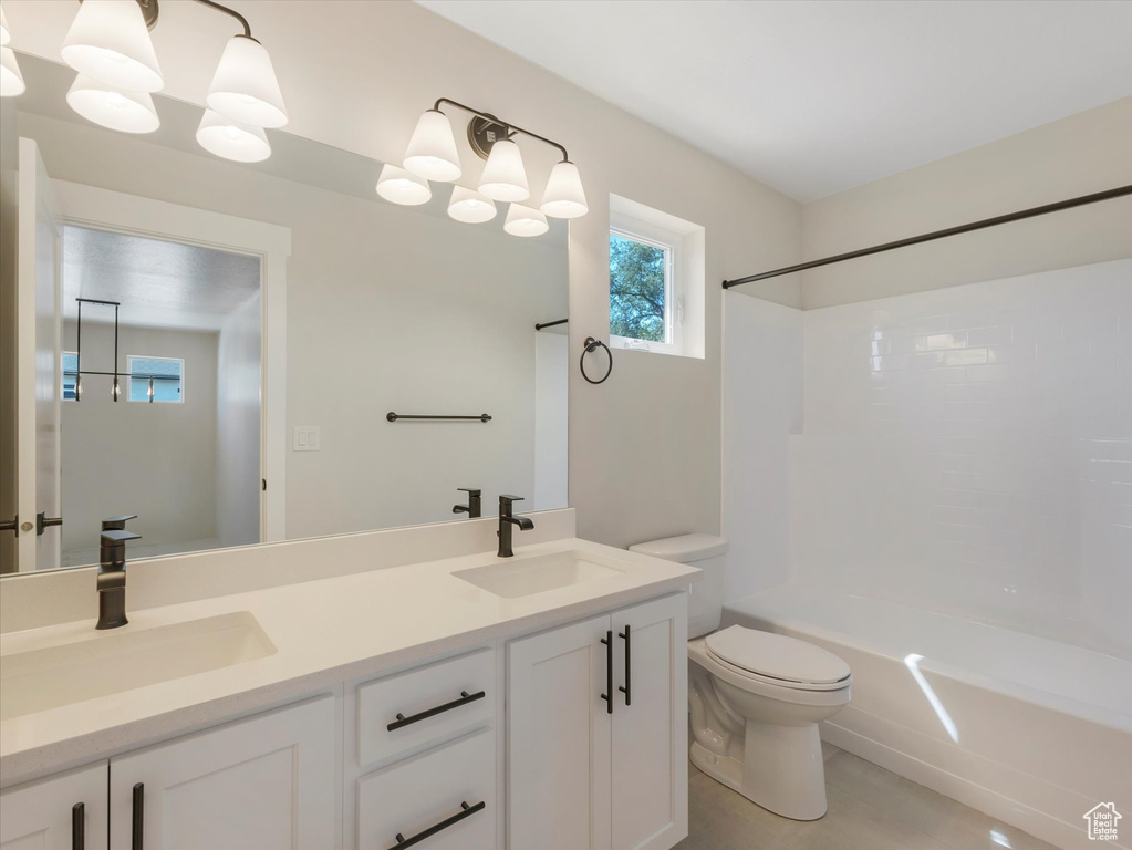 Full bathroom with dual bowl vanity, shower / bath combination, and toilet