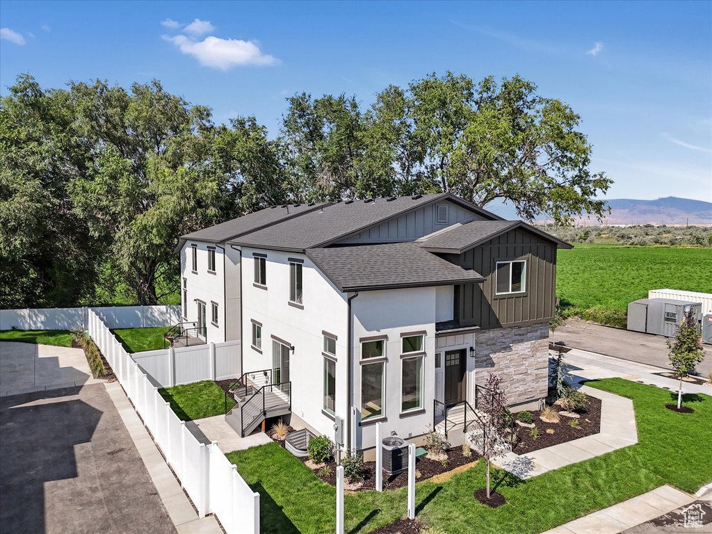 View of property exterior featuring central air condition unit, a mountain view, and a yard