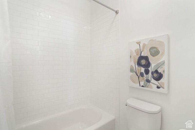 Bathroom featuring shower / bath combination with curtain and toilet