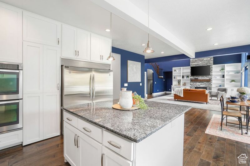 Kitchen featuring beamed ceiling, dark hardwood / wood-style flooring, stainless steel appliances, and white cabinetry