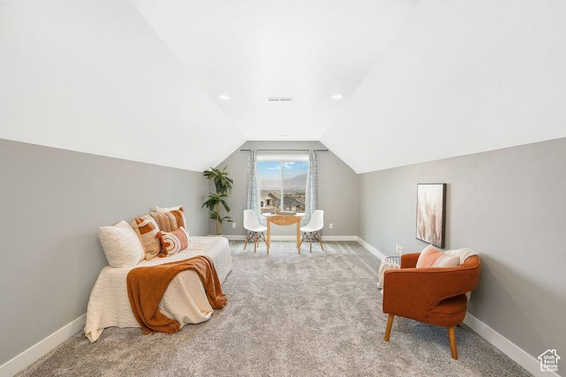 Sitting room featuring vaulted ceiling and carpet flooring