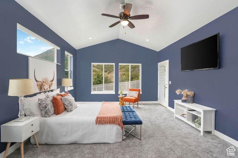 Carpeted bedroom with ceiling fan and lofted ceiling