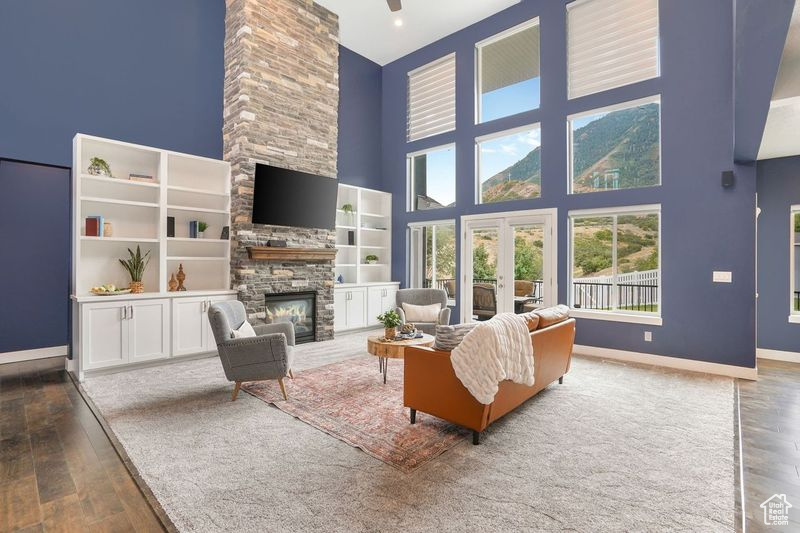 Living room featuring hardwood / wood-style floors, french doors, a stone fireplace, and a high ceiling