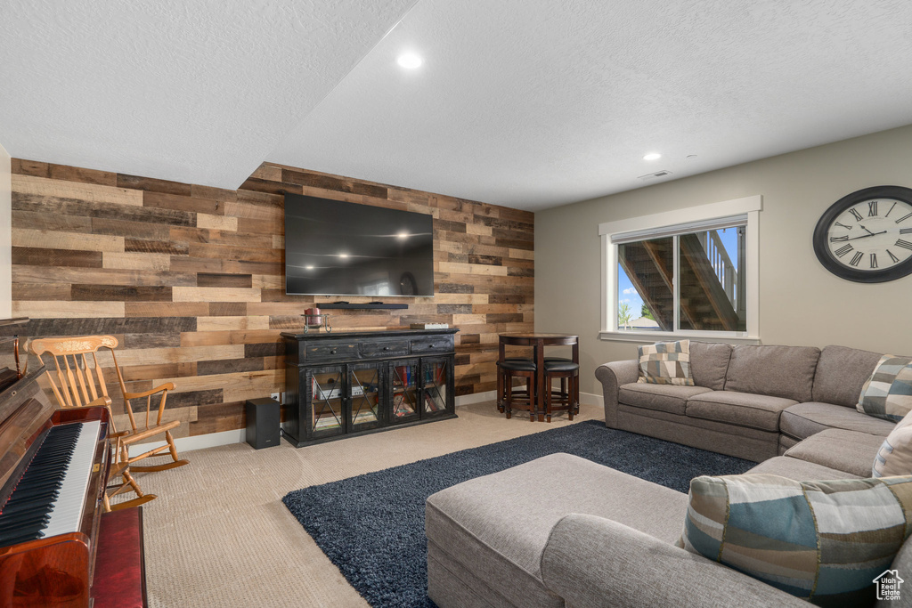 Carpeted living room with wooden walls and a textured ceiling