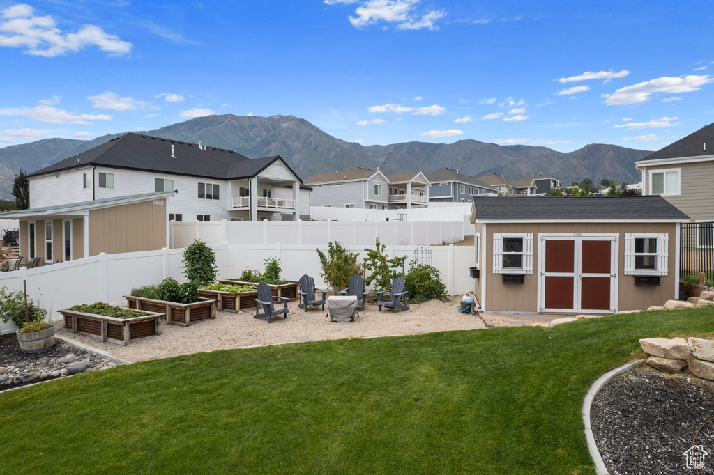 Back of house with a lawn, a mountain view, and an outdoor structure