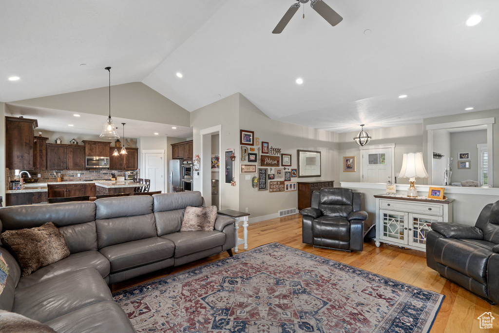 Living room featuring sink, light hardwood / wood-style flooring, vaulted ceiling, and ceiling fan