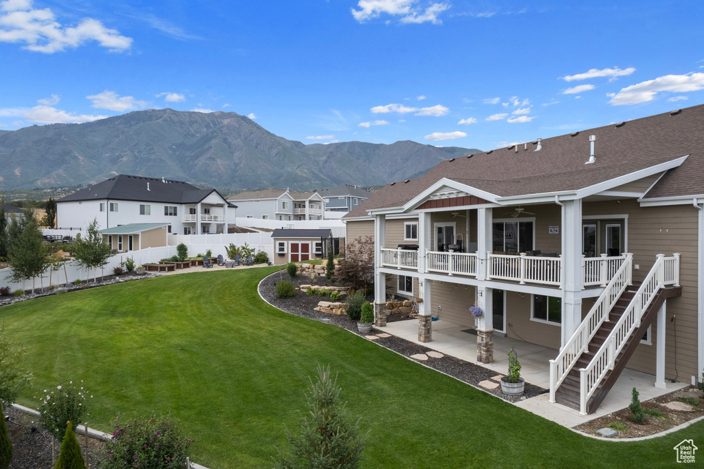 Back of house with a yard, a mountain view, and a patio area