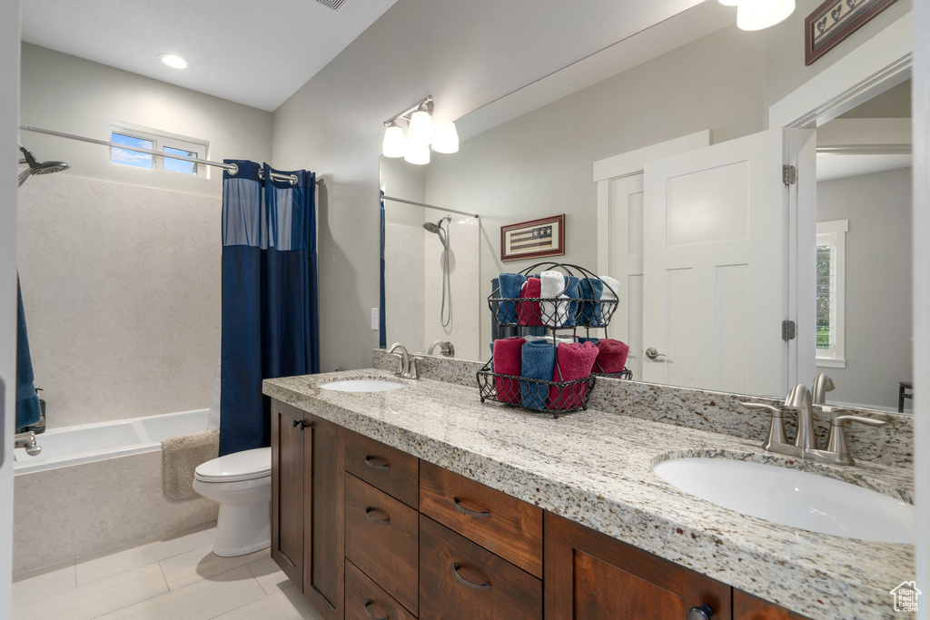 Full bathroom with toilet, shower / tub combo, tile patterned flooring, and dual bowl vanity