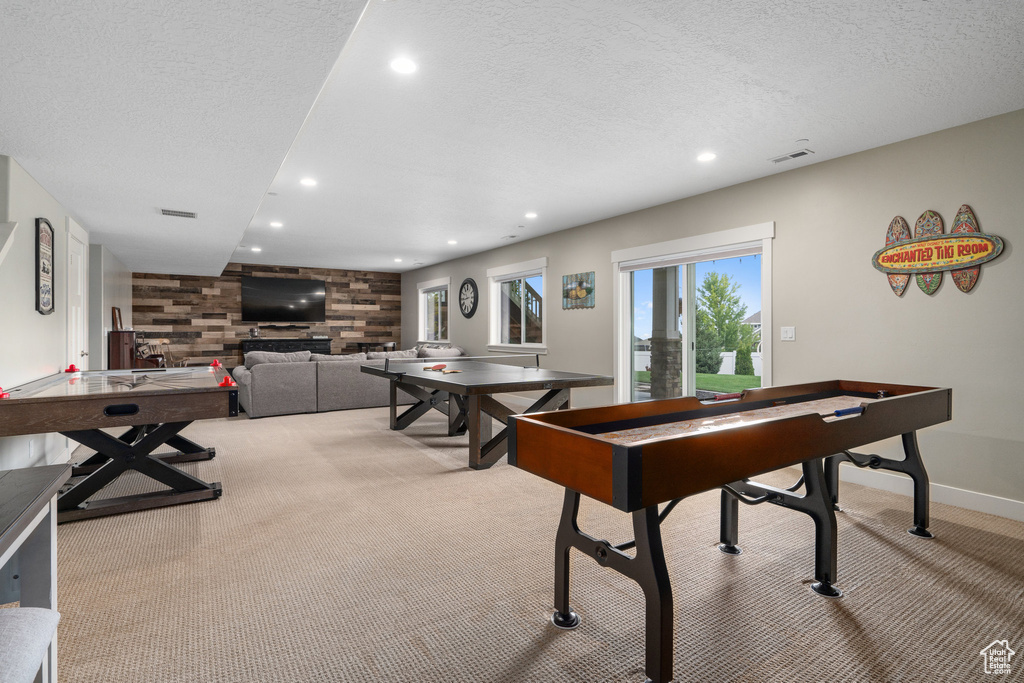 Playroom with wood walls, a textured ceiling, and light carpet