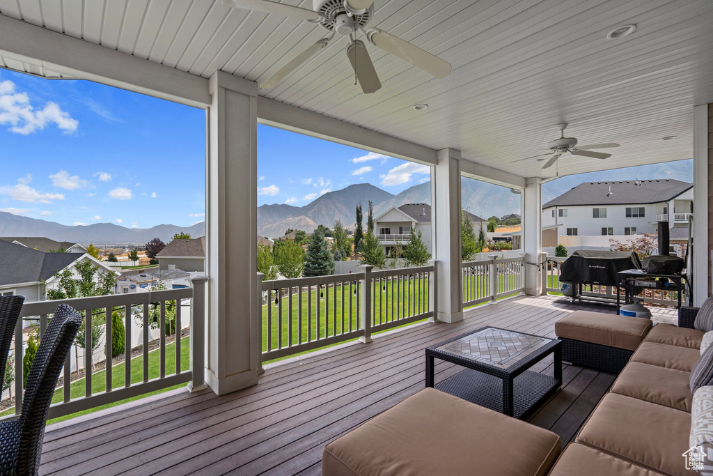 Wooden terrace with ceiling fan, a mountain view, and an outdoor living space