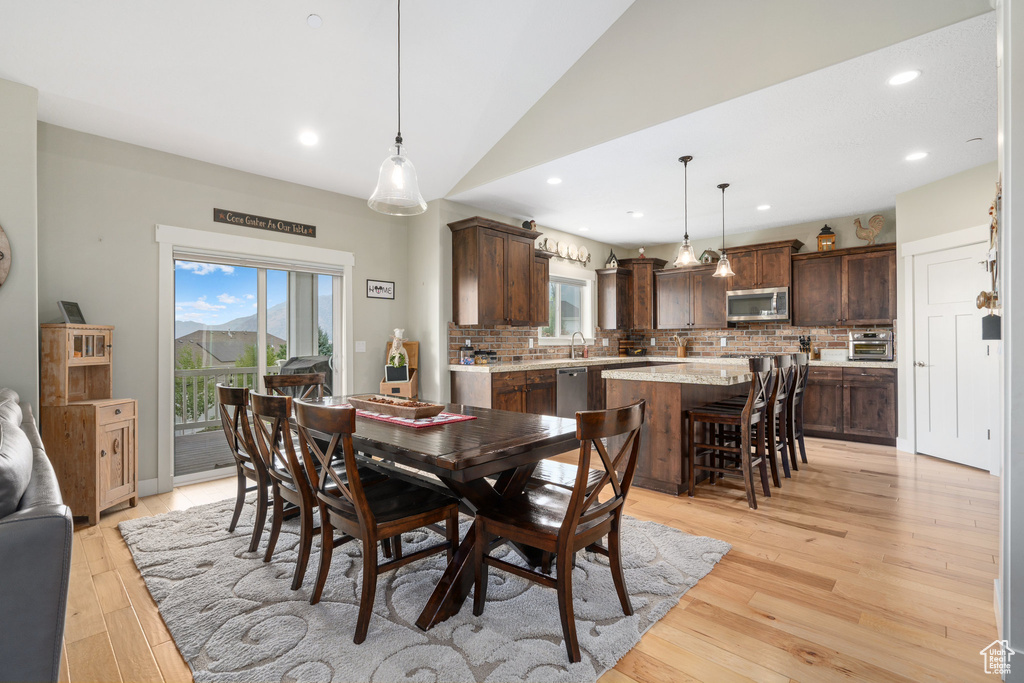 Dining space with sink, vaulted ceiling, and light hardwood / wood-style floors