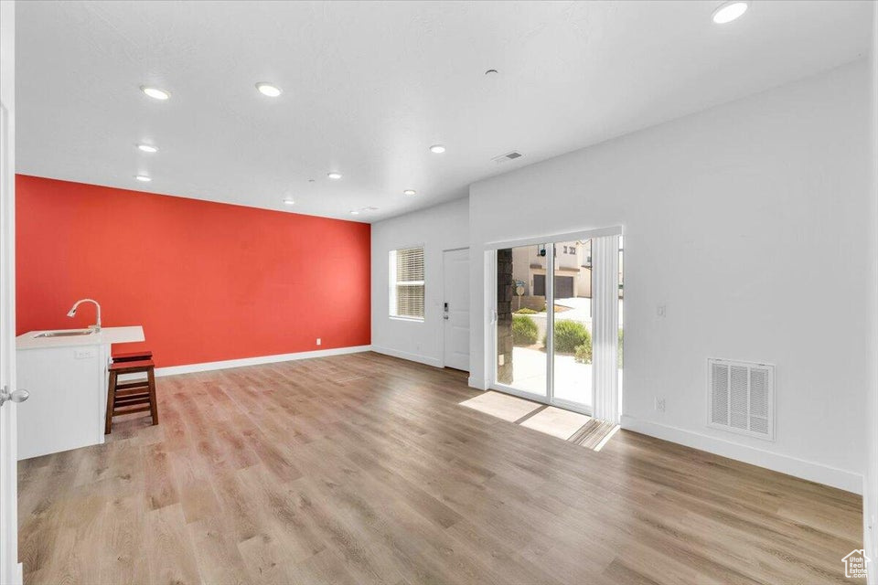 Unfurnished living room featuring sink and light wood-type flooring