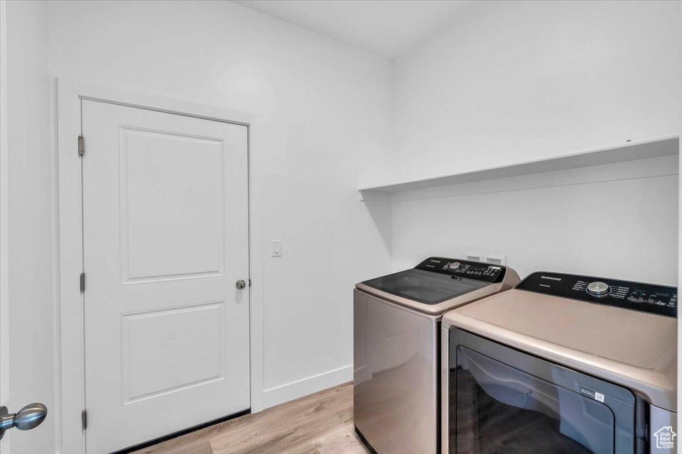 Laundry room with washing machine and dryer and light wood-type flooring