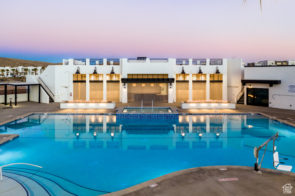 Pool at dusk featuring a community hot tub