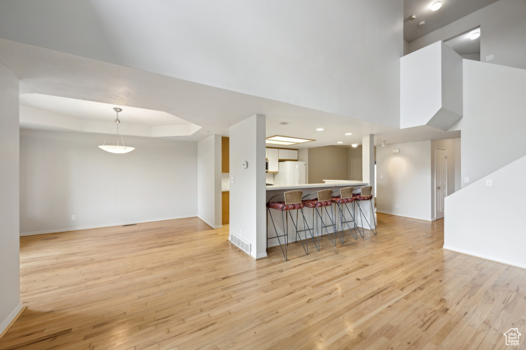 Living room featuring light hardwood / wood-style flooring, a high ceiling, and a raised ceiling