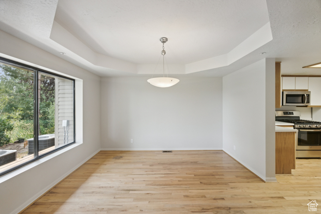 Dining area with light wood-type flooring and a raised ceiling