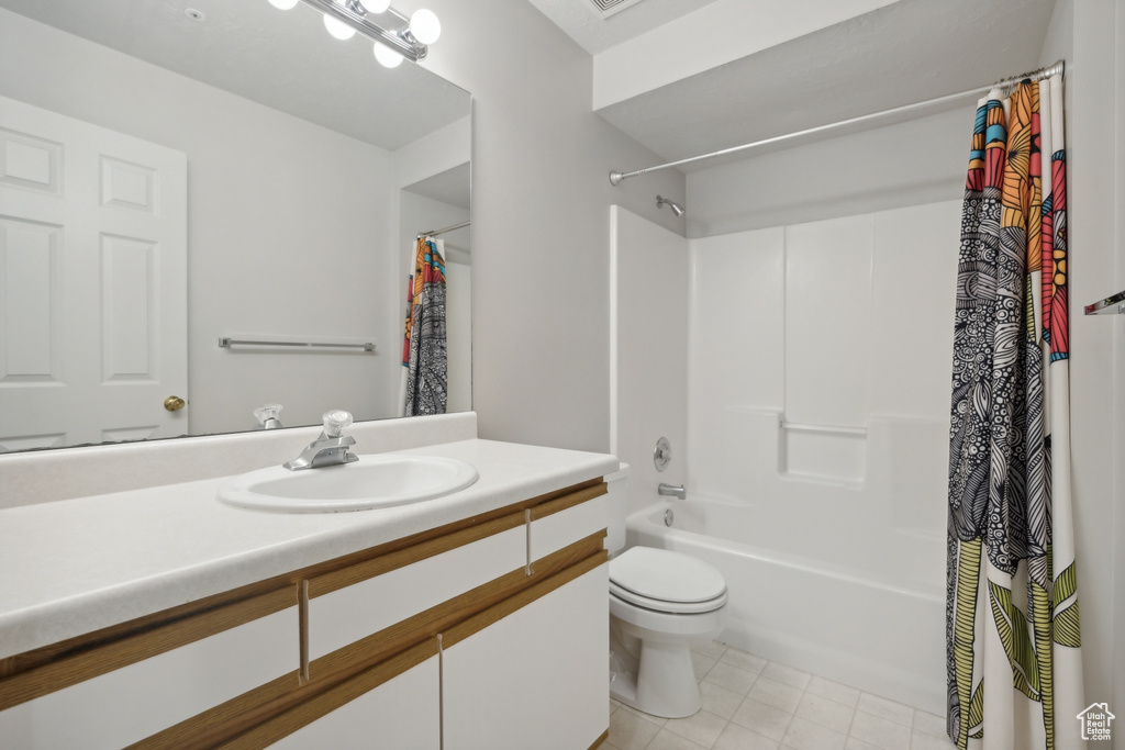 Full bathroom featuring shower / bathtub combination with curtain, toilet, vanity, and tile patterned flooring