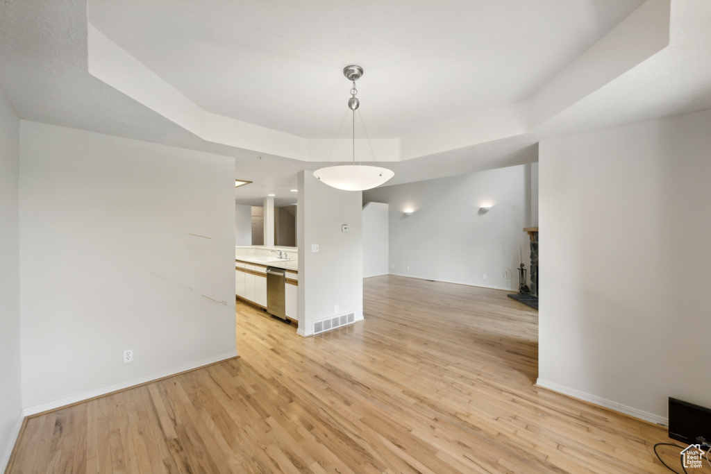 Unfurnished dining area with a raised ceiling and light hardwood / wood-style floors