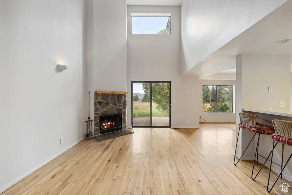 Living room featuring a towering ceiling, a fireplace, and light hardwood / wood-style floors