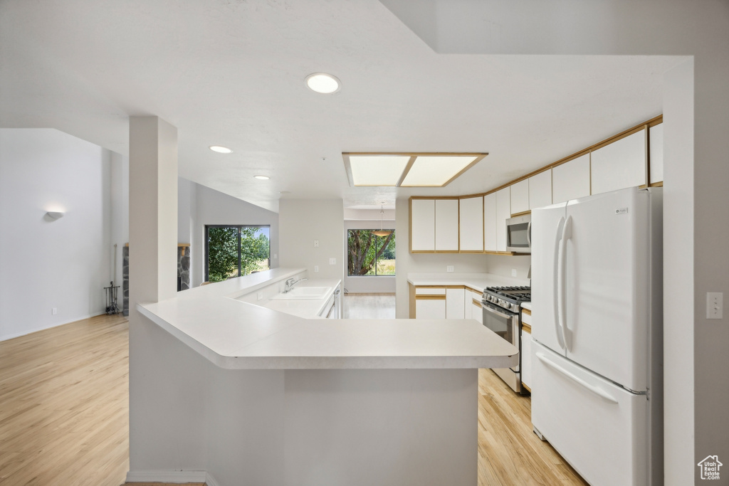 Kitchen featuring appliances with stainless steel finishes, sink, kitchen peninsula, and light hardwood / wood-style floors