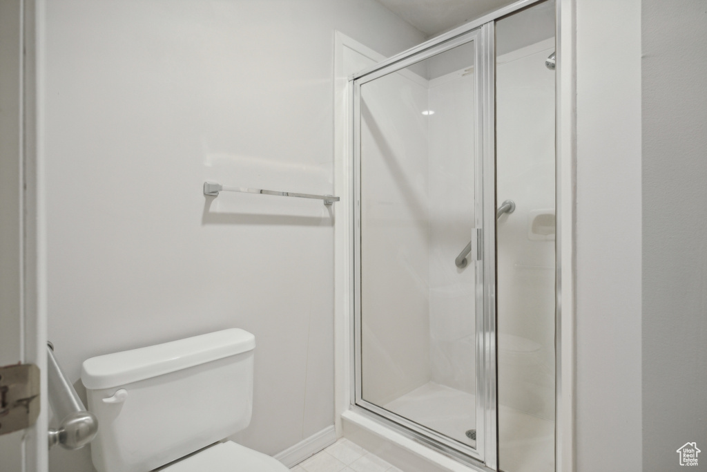 Bathroom featuring toilet, tile patterned floors, and a shower with shower door