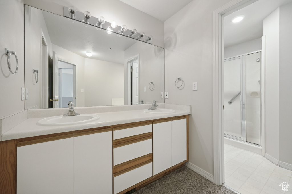 Bathroom featuring double sink vanity, walk in shower, and tile patterned flooring