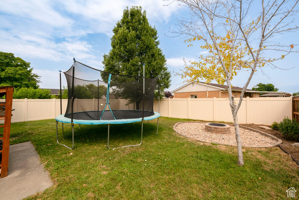 View of yard featuring a fire pit and a trampoline