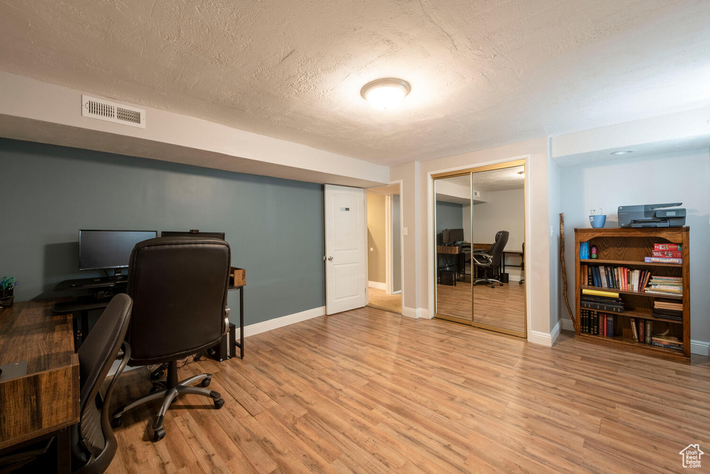 Office with a textured ceiling and light wood-type flooring