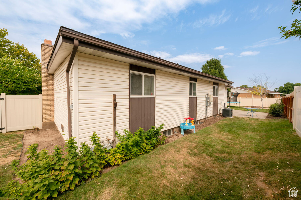 Rear view of property with a lawn and central AC