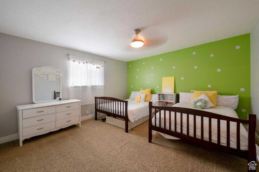 Carpeted bedroom with a textured ceiling and ceiling fan