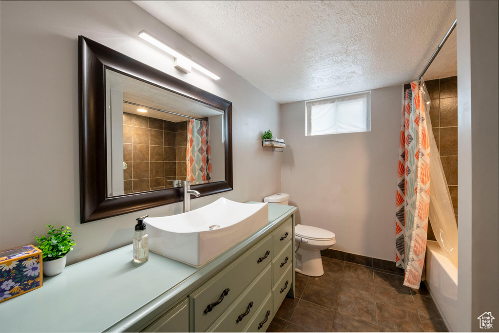 Full bathroom featuring vanity, shower / tub combo, toilet, and a textured ceiling