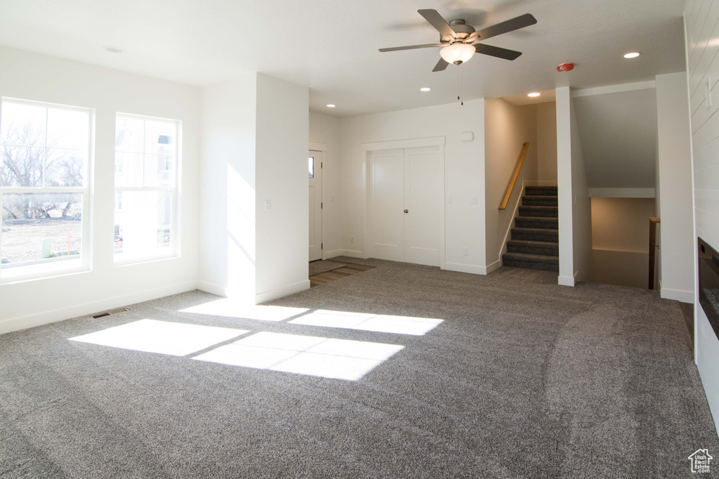 Unfurnished room featuring ceiling fan, light colored carpet, and a healthy amount of sunlight