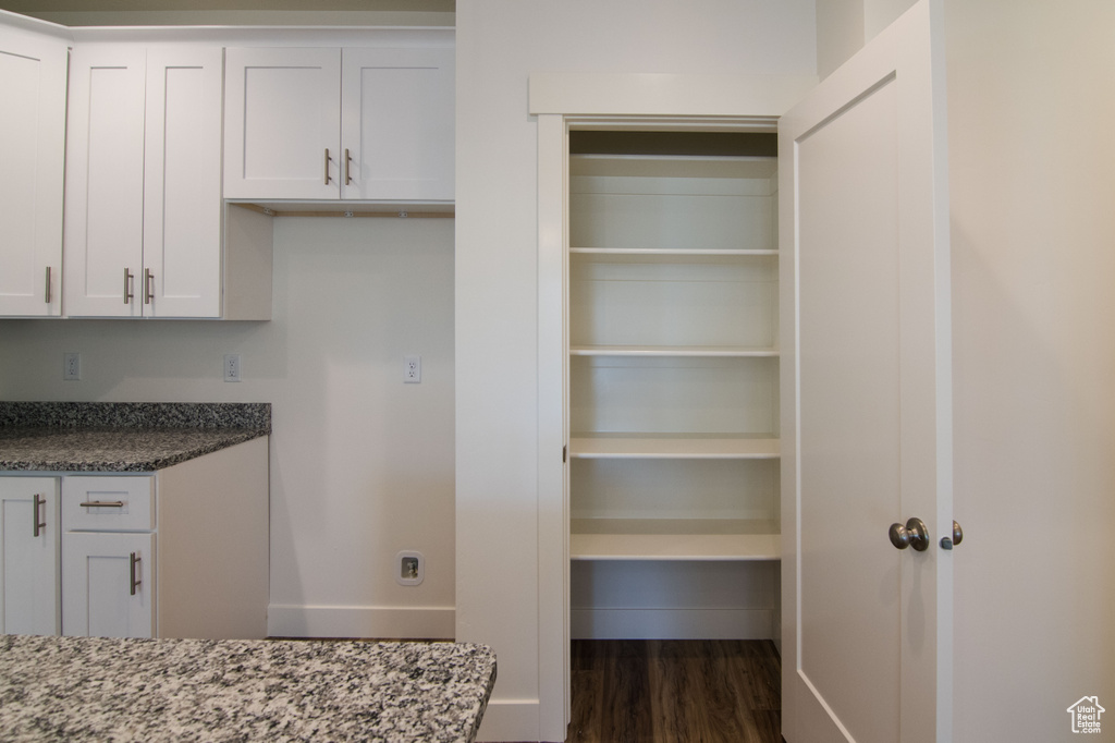 Interior space featuring stone counters, dark wood-type flooring, and white cabinetry