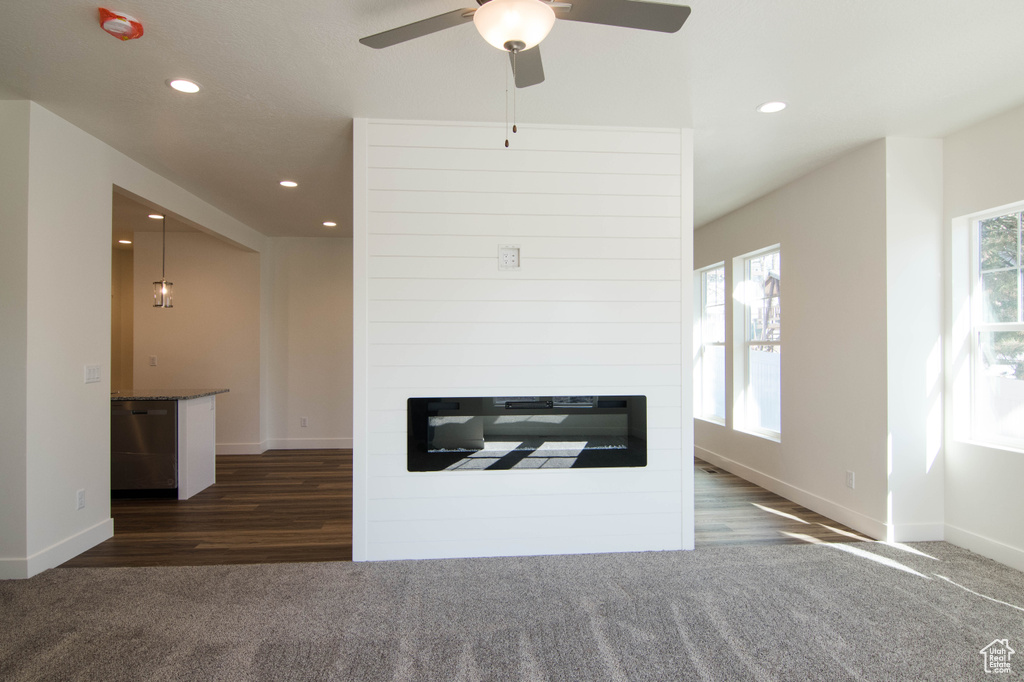 Carpeted living room with plenty of natural light and ceiling fan